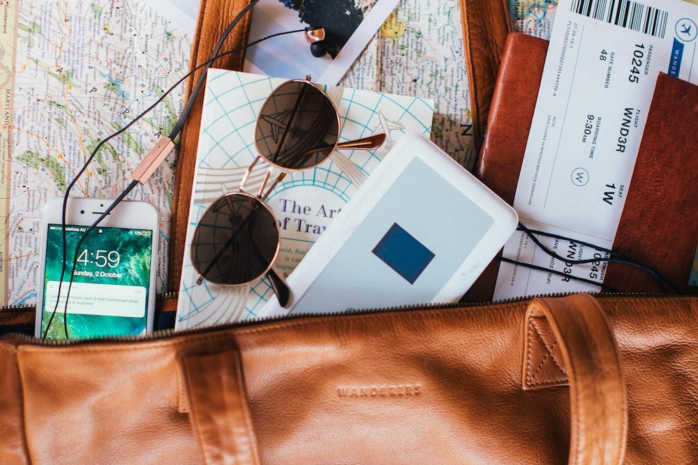 Leather bag with sunglasses, phone and boarding passes in it